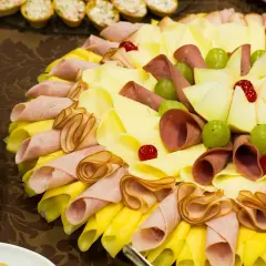 Un buffet froid facile et pas cher : plateau de charcuterie, fromages roulés, raisins verts et cerises confites.