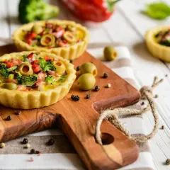 Mini quiches colorées sur fond de bois blanc, une idée pour que faire avec un reste de pâte brisée.
