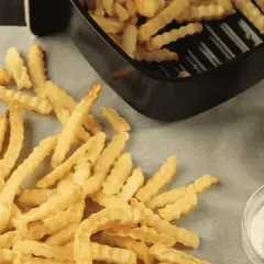 Frites maison ondulées, croustillantes et dorées, tout juste sorties de l'airfryer Ninja. Servies avec ketchup et mayonnaise.