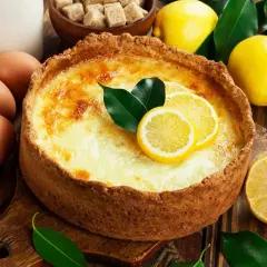 Un délicieux flan au citron, garni de rondelles de citron et de feuilles vertes, entouré de citrons frais, d'œufs et de sucre.