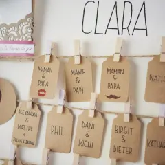 Disposition table mariage : étiquettes en kraft avec noms des invités, accrochées à des fils de chanvre. Décoration champêtre pour un mariage.