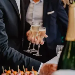 Des flûtes de champagne pétillant pour le vin d'honneur mariage. Des canapés colorés et une bouteille de champagne en avant-plan.