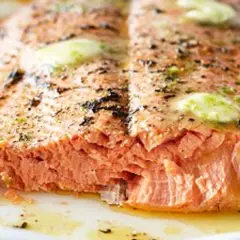 Un pavé de saumon barbecue, cuit à la perfection, avec des éclats de beurre fondant et des herbes.