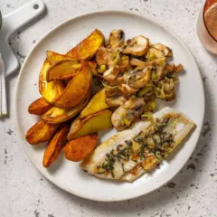 Filet de merlu avec peau à la poêle, accompagné de pommes de terre rôties et d'une poêlée de champignons et poireaux.