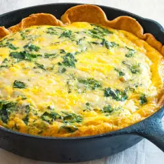 Quiche aux épinards dans une poêle en fonte, parfaite pour une recette jaune d'oeuf.