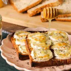 Une tartine alsacienne gourmande, garnie de fromage de chèvre fondant et arrosée de miel doré. Un délice à savourer !