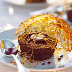 Gâteau au chocolat surmonté d'une décoration caramel facile et aérienne, avec une cuillère de sauce au chocolat.