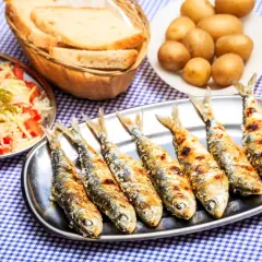 Sardines grillées sur un plateau, accompagnées de pommes de terre, salade et pain. La cuisson des sardines sans odeur est un vrai délice !