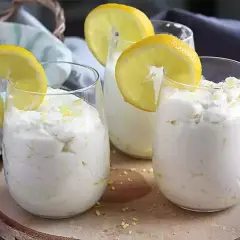 Trois verres de mousse au citron sans cuisson, décorés de rondelles de citron et de zeste. Un dessert frais et léger.