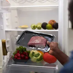Un homme regarde un morceau de viande dans son emballage. Il se demande : viande hors frigo combien de temps ?