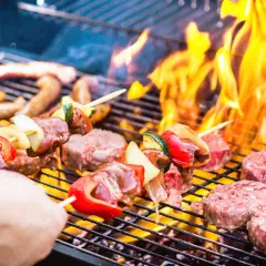 Brochettes et steaks sur un barbecue en feu. La conservation de la viande cuite au barbecue est essentielle pour profiter des restes.