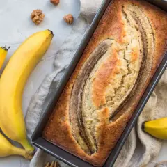 Gâteau moelleux à la banane trop mûre, cuit à la poêle, avec des bananes fraîches et des noix autour.