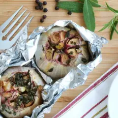Deux têtes d'ail au barbecue, enveloppées dans du papier d'aluminium, avec des herbes et des épices.