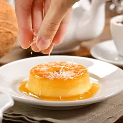 Un flan au lait de coco sans four, garni de noix de coco râpée, prêt à être dégusté avec un café.