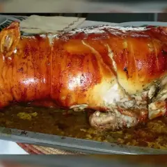 Un magnifique cochon de lait farci, rôti à la perfection, avec une peau dorée et croustillante, prêt à être dégusté.