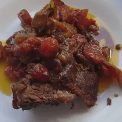 Un morceau de côte de bœuf mijoté, nappé d'une sauce aux tomates et oignons caramélisés. Parfait pour une marinade pour côte de bœuf maison.