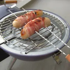 Deux boudins blancs enroulés de lard grillent sur un barbecue. Un délice pour un barbecue estival.