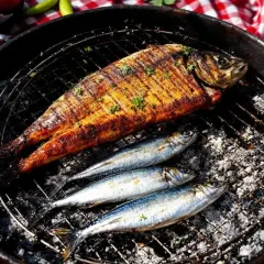 Poisson grillé et sardines sur un barbecue. Faut-il écailler les sardines avant de les griller ? La réponse est dans l'image.
