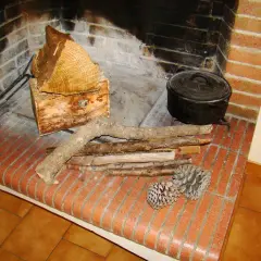 Prêt à allumer le feu avec des pommes de pin, du petit bois et des bûches. Une marmite en fonte est posée près du foyer.