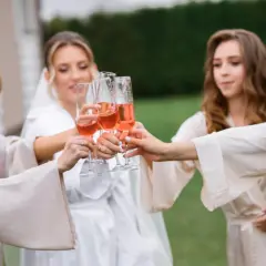 Cinq femmes portent des robes de chambre en soie et portent des verres de champagne rosé pour un vin d'honneur à 16h.