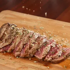 Un succulent côte de bœuf, tranché et parsemé d'herbes, prêt à être dégusté. Une croûte de sel subtile rehausse sa saveur.