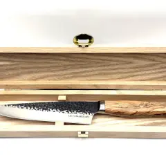 Un magnifique couteau au barbecue, avec une lame martelée et un manche en bois d'olivier, repose dans son coffret en bois.