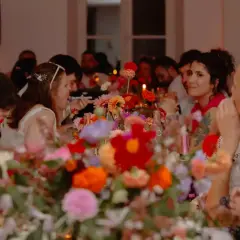 Des invités souriants partagent un repas de mariage festif, entourés de fleurs colorées. La durée du repas semble agréable.