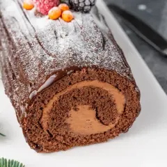 Bûche de Noël au chocolat, parfaite pour une recette génoise bûche moelleuse. Garnie de fruits rouges et de sucre glace.