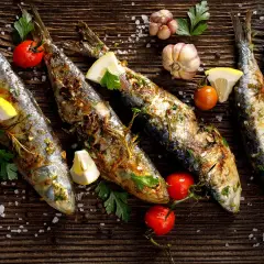 Sardines grillées, citron, tomates cerises et ail sur fond de bois. Faut-il vider les sardines avant de les cuire ?
