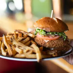 Un délicieux burger montagnard, croustillant et garni, servi avec une généreuse portion de frites dorées.