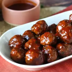 Un plat de boulettes de viande barbecue, brillantes et appétissantes, baignant dans une sauce sucrée. Parfaites pour un apéritif ou un repas convivial.