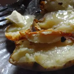 Pommes de terre cuites dans la cendre, ouvertes et garnies de beurre fondant. Un délice simple.