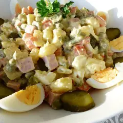Salade Olivier généreuse, garnie d'œufs durs, de cornichons et de persil frais. Un délice pour les papilles.