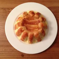Charlotte à l'orange, un dessert doré et moelleux, servi sur une assiette blanche.