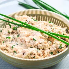 Un bol de rillettes de thon à la crème fraîche, garni de ciboule fraîche. Un délice crémeux et savoureux.