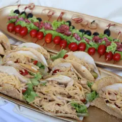 Un buffet froid mariage avec des tacos garnis de poulet, salade et fromage râpé, et des brochettes de tomates, olives et salami.