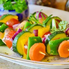 Brochettes de légumes colorées, une excellente idée accompagnement barbecue. Courgettes, poivrons, carottes, tomates et oignons rouges assaisonnés.
