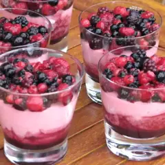Plusieurs verrines de **dessert léger aux fruits rouges surgelés**, garnies de baies fraîches et d'une mousse rose.