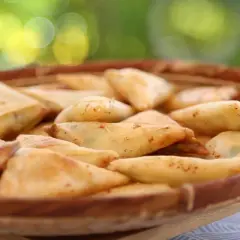 Un panier rempli de samoussas dorés, garniture pomme de terre fromage. Parfait pour un apéritif gourmand en extérieur.