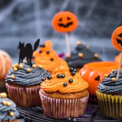 Des muffins d'Halloween effrayants, parfaits pour une recette facile. Glaçage orange et gris, décorés de citrouilles et d'un chat noir.