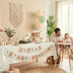 Joyeux 1er anniversaire ! Un buffet décoré avec un ballon chiffre 1, des guirlandes et des cadeaux pour un buffet anniversaire fille 1 an.
