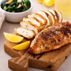 Poulet grillé, tranché, avec quartiers de citron, épinards et un verre de jus. Un plat savoureux, même s'il est resté hors du frigo 24h.