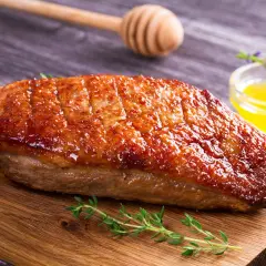 Magret de canard grillé à la perfection, prêt pour la cuisson barbecue gaz. Servi avec une sauce dorée et des herbes fraîches.