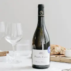 Bouteille de Pouilly-Fuissé, deux verres à vin, pain, fromage de chèvre et jambon. Parfait pour une liste boisson mariage.