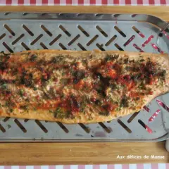 Filet de truite au four, parsemé d'herbes et de baies roses, prêt à être dégusté.