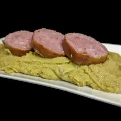 Trois tranches de saucisse sur une purée de pois cassés, un plat réconfortant.