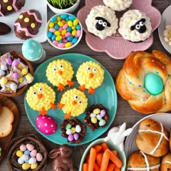 Table garnie de douceurs pascales : cupcakes moutons, poulets, biscuits abeilles, pains tressés, chocolats et bonbons. Parfaites recettes rigolotes pour Pâques !