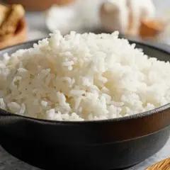 Un bol de riz blanc moelleux, prêt à être dégusté. Saviez-vous pourquoi rincer le riz avant cuisson ? Cela enlève l'excès d'amidon pour un résultat plus léger.