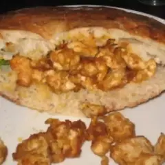 Un pain garni de morceaux de poulet épicés, prêt à déguster. Une recette kebab maison facile pour un repas savoureux.