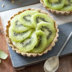 Délicieux dessert kiwi, une tartelette garnie de crème et de fines rondelles de kiwi, prête à être dégustée.